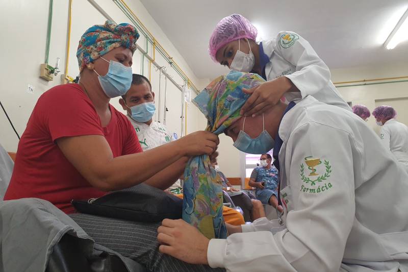 Paciente Suelem aprendendo a colocar o lenço em um voluntário.