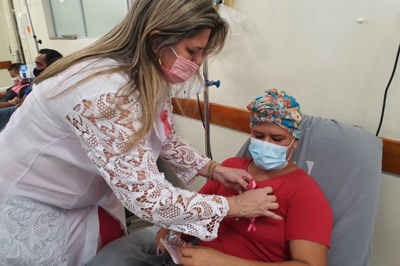 A chefe da Divisão de Farmácia, Annie Oliveira, coloca o laço na paciente Suelem da Silva.