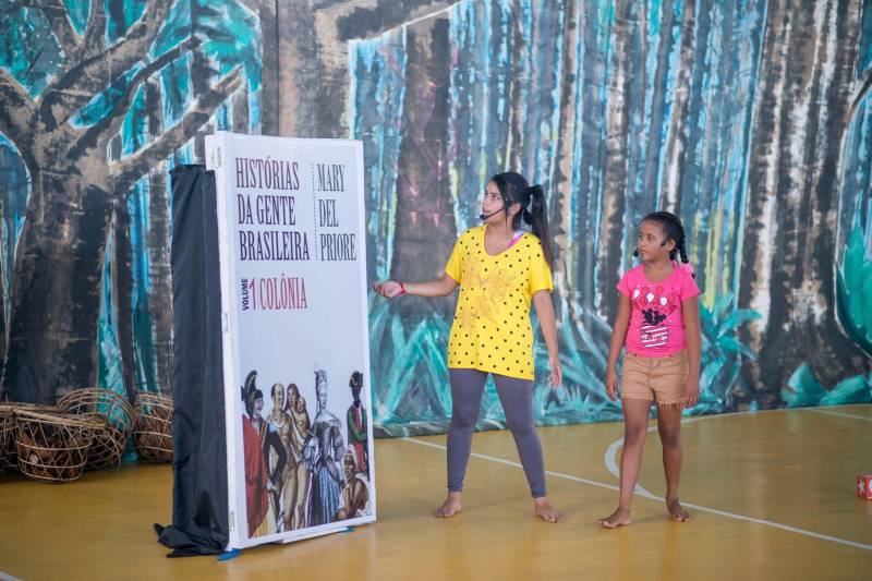 O sentimento de pertencimento à uma história verdadeira, foi fortalecido nesta manhã (06). O ginásio da Universidade Federal Rural da Amazônia - UFRA recebeu 40 alunos do Pro Paz nos Bairros (PPB), polos UFRA, UFPA, UIPP Terra Firme e Mangueirão, para dar vida a obra “História da gente brasileira”, da escritora Mary Del Priore, com a encenação do espetáculo "Terra à vista” (foto). A montagem foi apresentada no Sarau Literário do Livro Solidário, a convite da Imprensa Oficial do Estado. O espetáculo dirigido pelos arte educadores Glaucia Pinto e Elton Santos, sob orientação de Luci Azevedo, coordenadora do PPB é reflexo de um processo que envolve toda a equipe dos polos, resultando na construção do cenário, figurino, trilha sonora que reproduziu o que o livro ensina: o que vestiam, onde moravam, o que comiam e o que faziam os primeiros habitantes do Brasil. As rodas de leituras do livro de Mary e uma aula aberta, com o historiador Aldrin Figueiredo, no Museu de arte sacra, no mês de maio, foram fundamentais para encher de sentimentos e veracidade este espetáculo.

FOTO: FERNANDO SETTE CÂMARA / ASCOM IOE
DATA: 06.06.2018
BELÉM - PARÁ <div class='credito_fotos'>Foto: FERNANDO SETTE CÂMARA / ASCOM IOE   |   <a href='/midias/2018/originais/cf1fd213-ac43-4a84-a009-dba57367741c.jpg' download><i class='fa-solid fa-download'></i> Download</a></div>