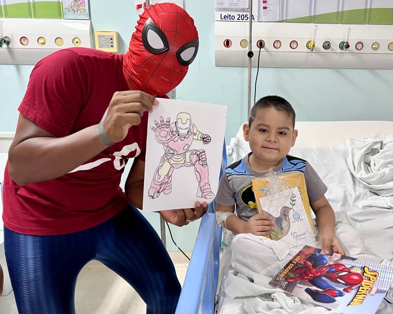 Ao receber livros, o pequeno Calebe, de 6 anos, presenteia voluntário com um desenho pintado por ele