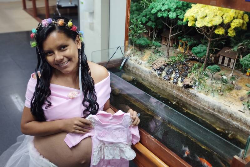 Mayra Lopes com roupinha de sua bebê. 