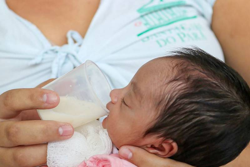 bebê recebe leite humano no copinho