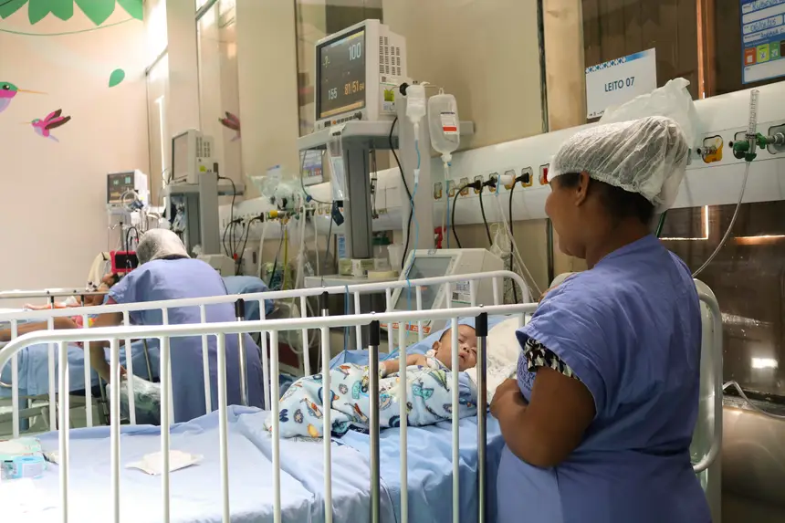 Mãe usando a bata hospitalar para a proteção do filho