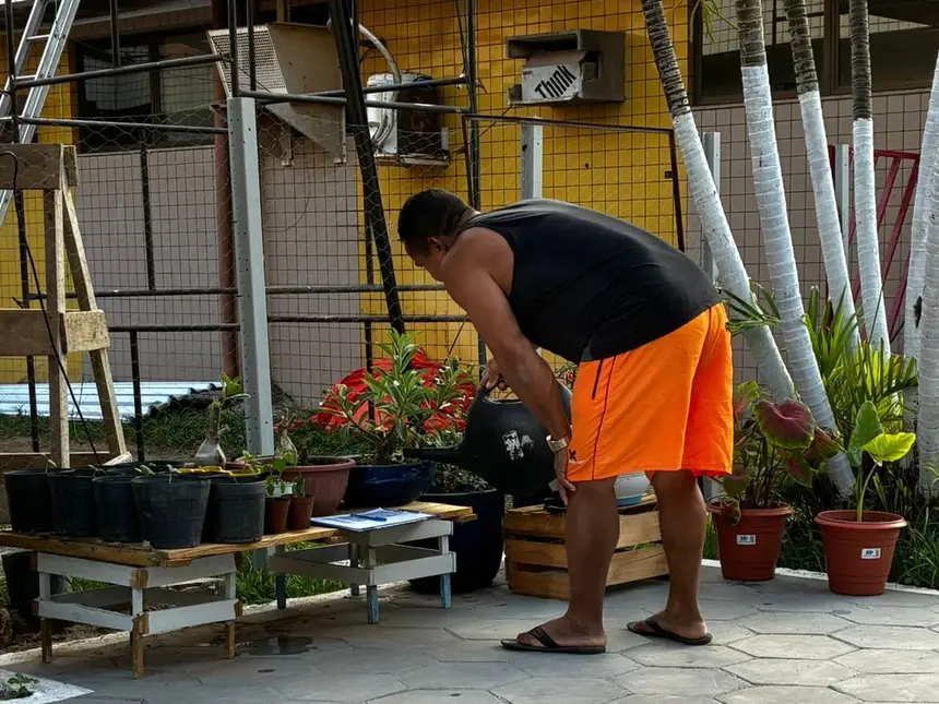 Usuário rega plantas na área arborizada do HGT, durante atividade de reabilitação conduzida pela equipe de Fisioterapia.